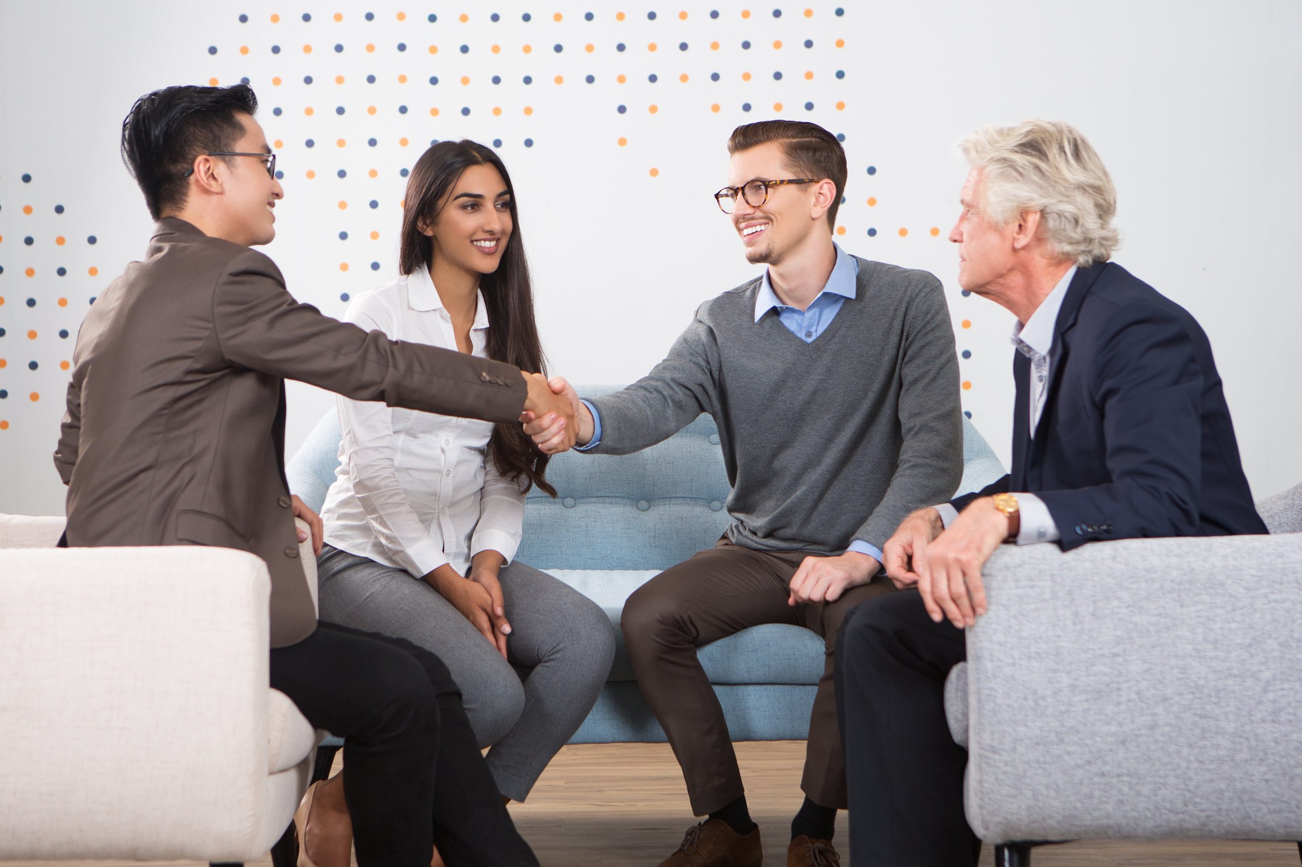 smiling-business-partners-shaking-hands-lounge-min