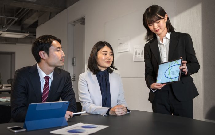Singapore corporate team discussing business strategy and entity structures while reviewing a chart on a tablet.