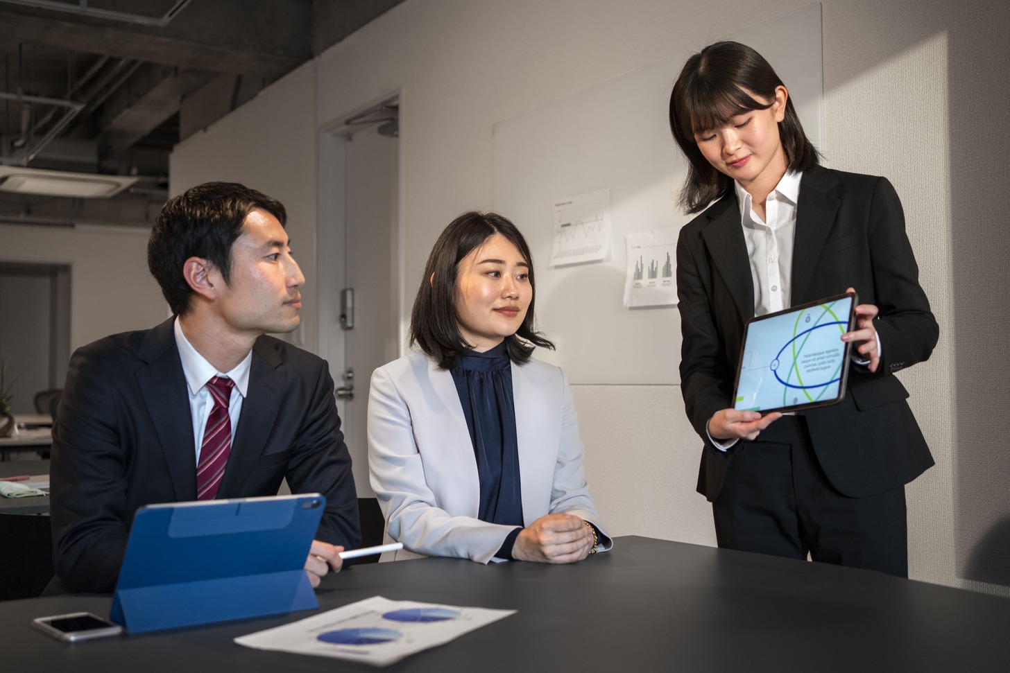 Singapore corporate team discussing business strategy and entity structures while reviewing a chart on a tablet.