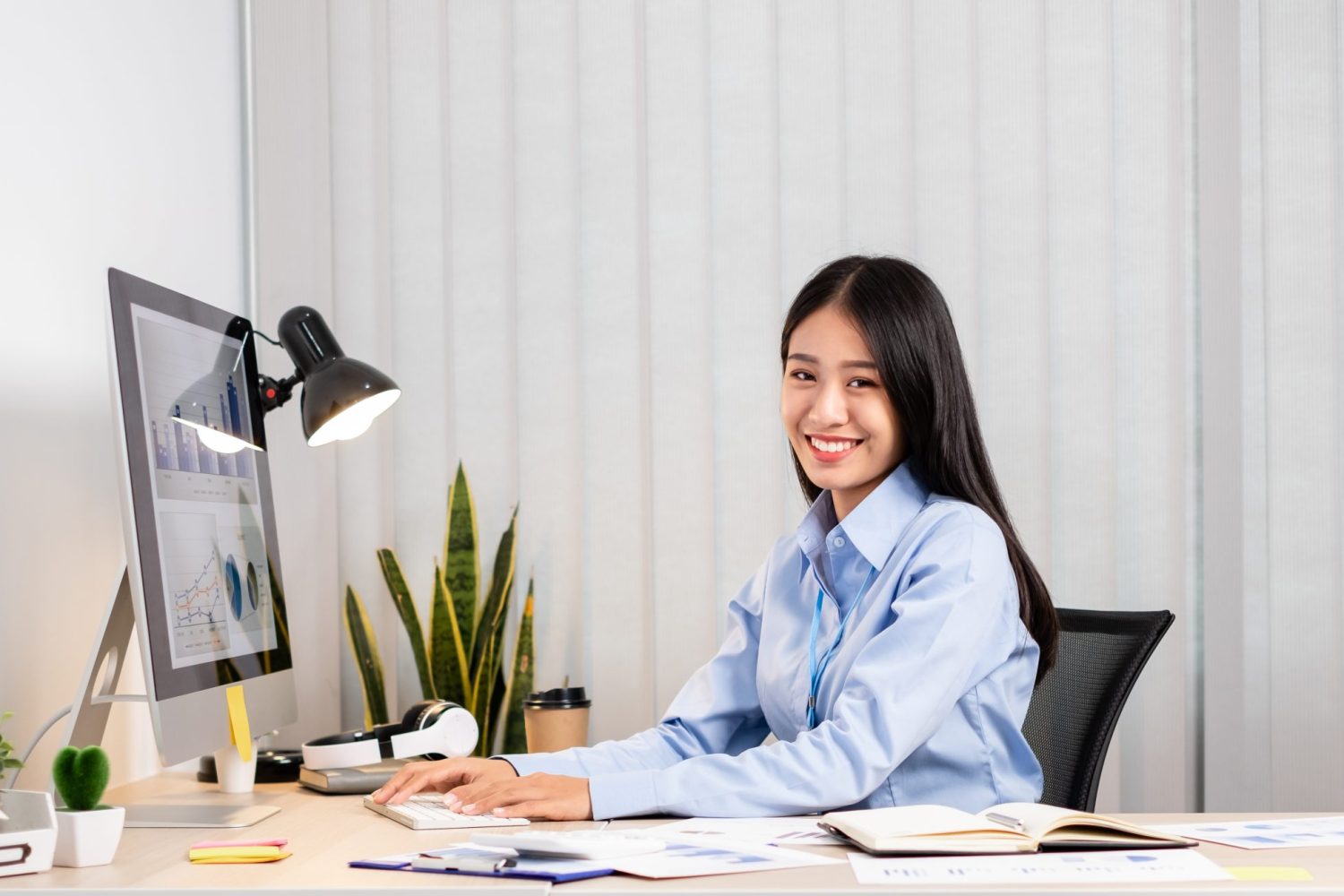 Asian woman working on a laptop with a cheerful and happy smile while working at the office.